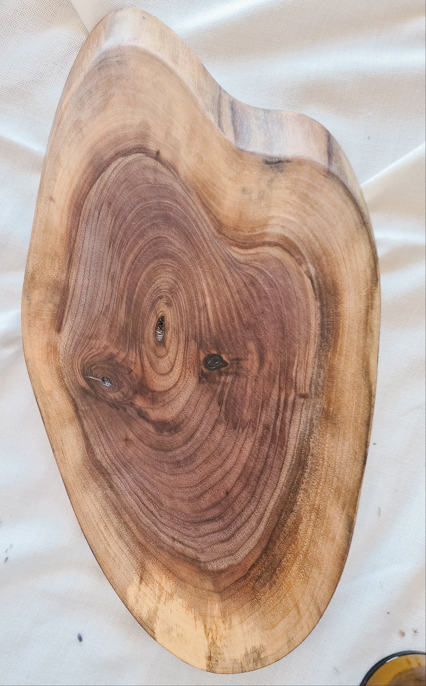 Wooden cutting board with a heart-shaped cutout on a white fabric background