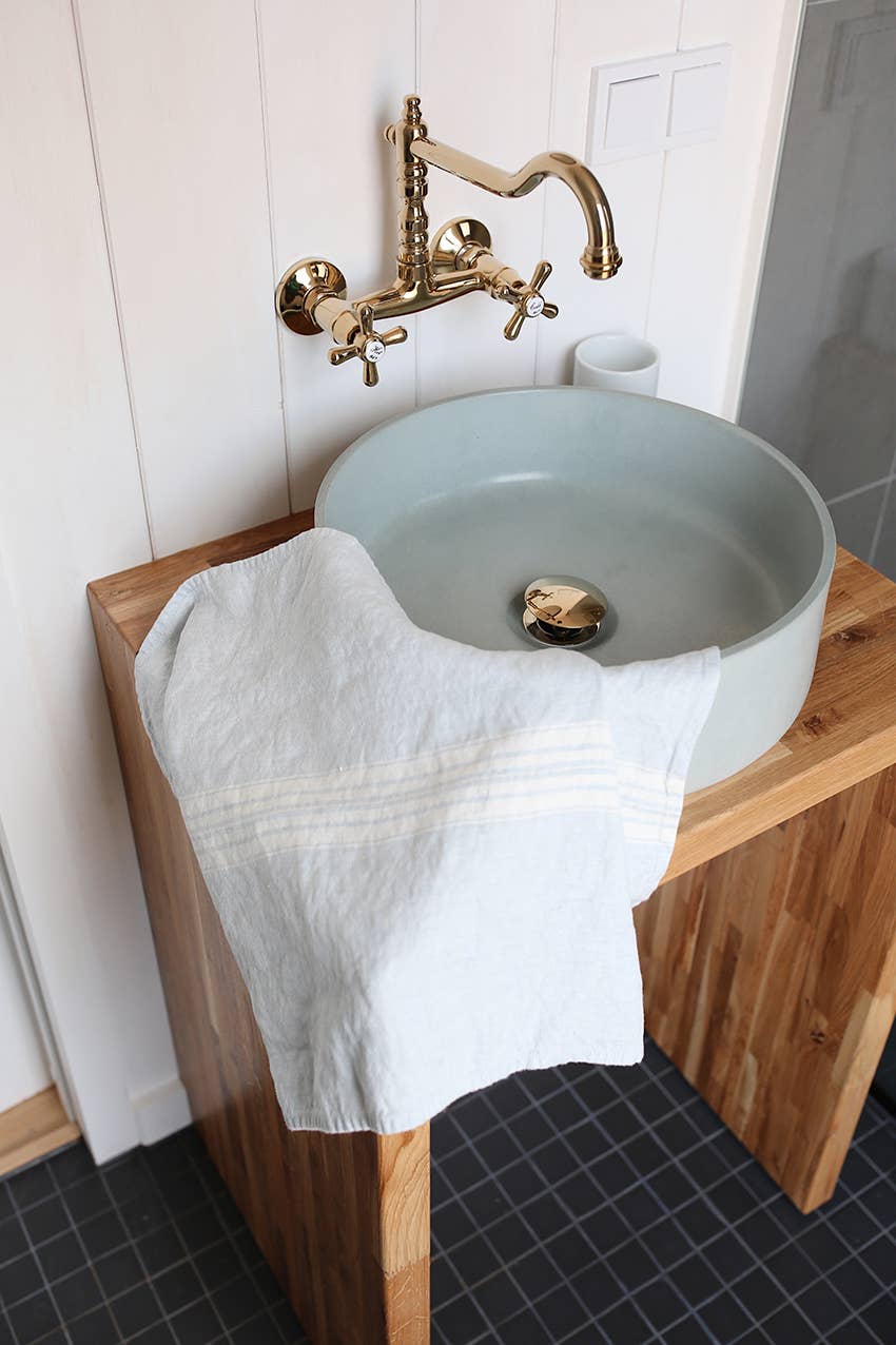 Bathroom sink with wooden countertop and gold faucet