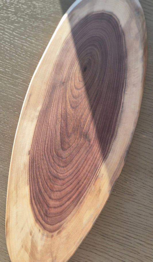 Wooden serving board with a natural grain pattern on a gray surface