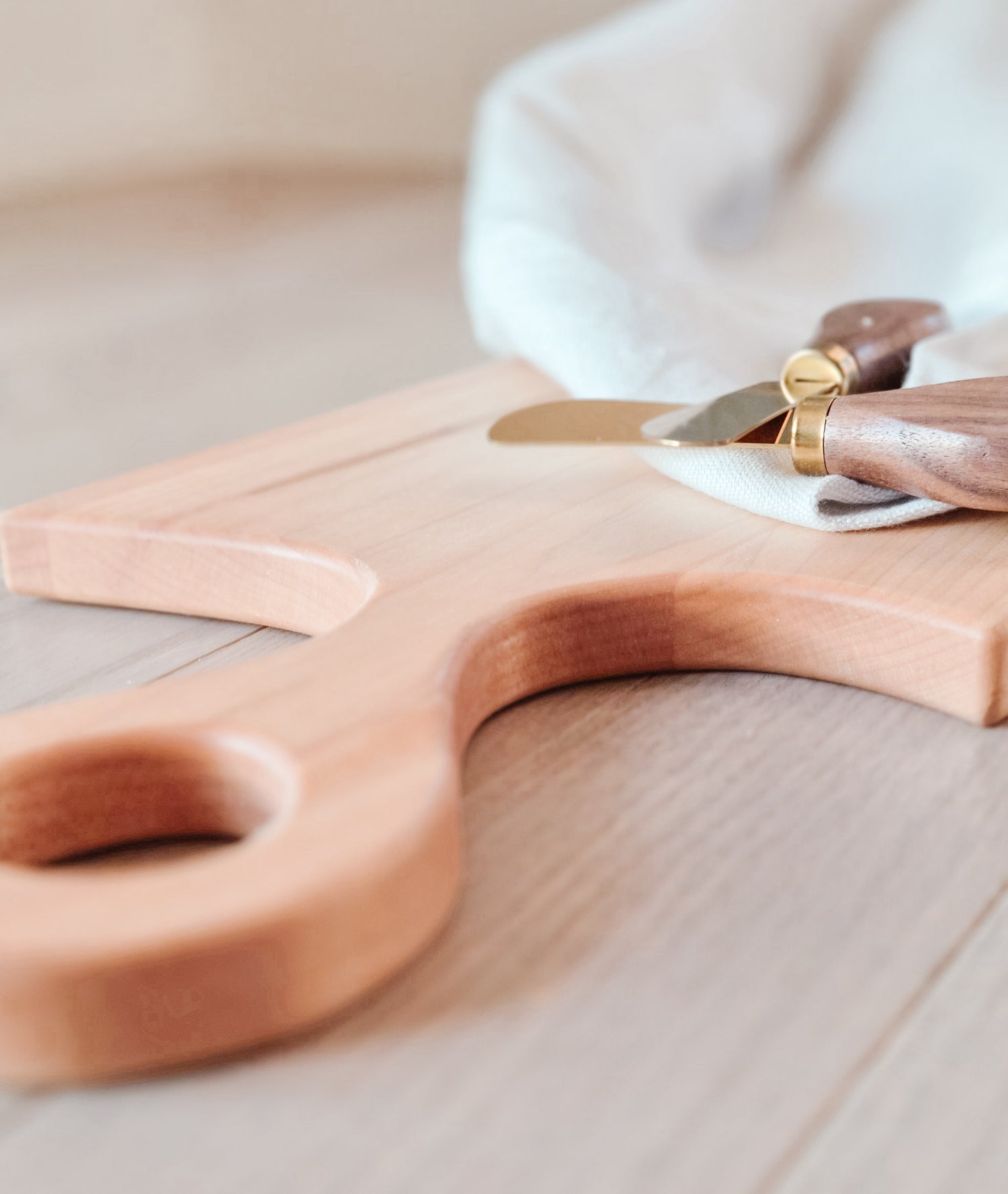 Wooden cutting board with a knife on a light wooden surface