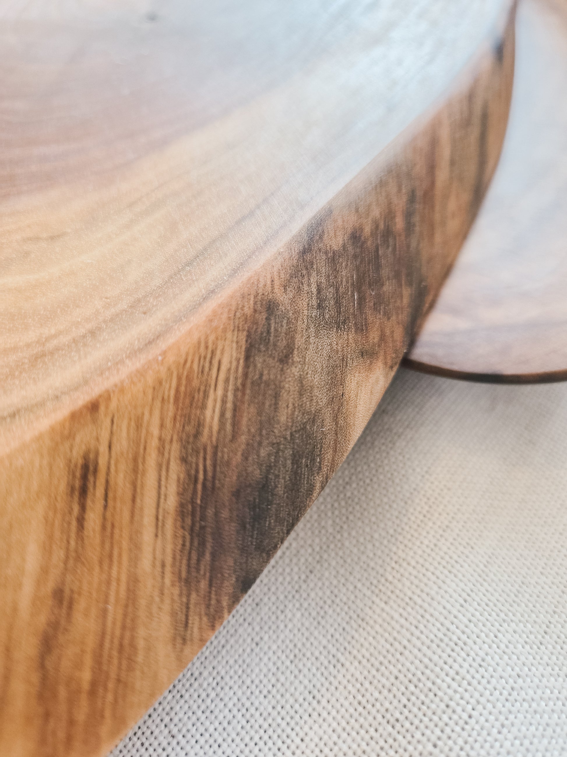 Close-up of a wooden surface with a textured edge on a light gray background