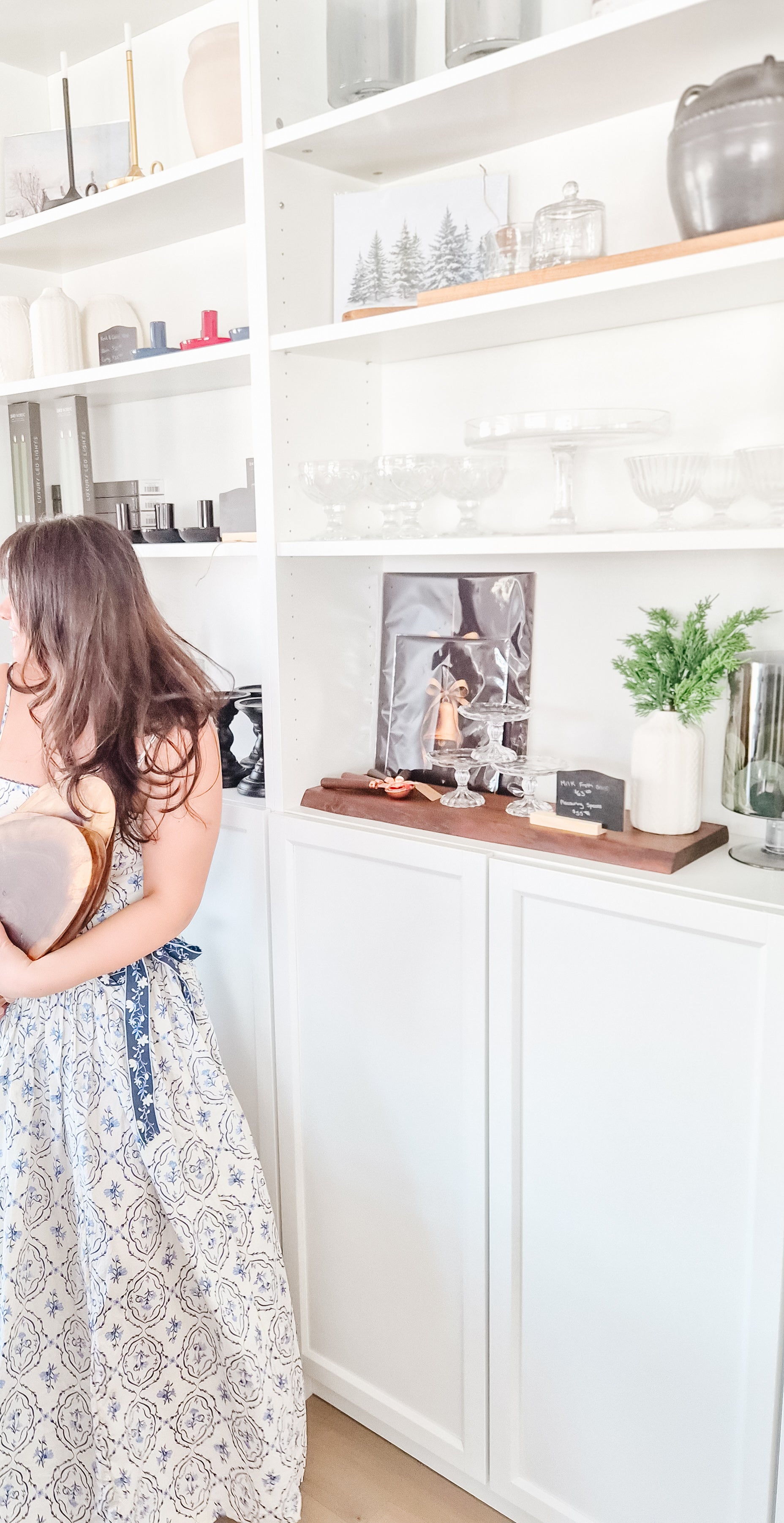 Woman standing in a kitchen with white shelves and decor