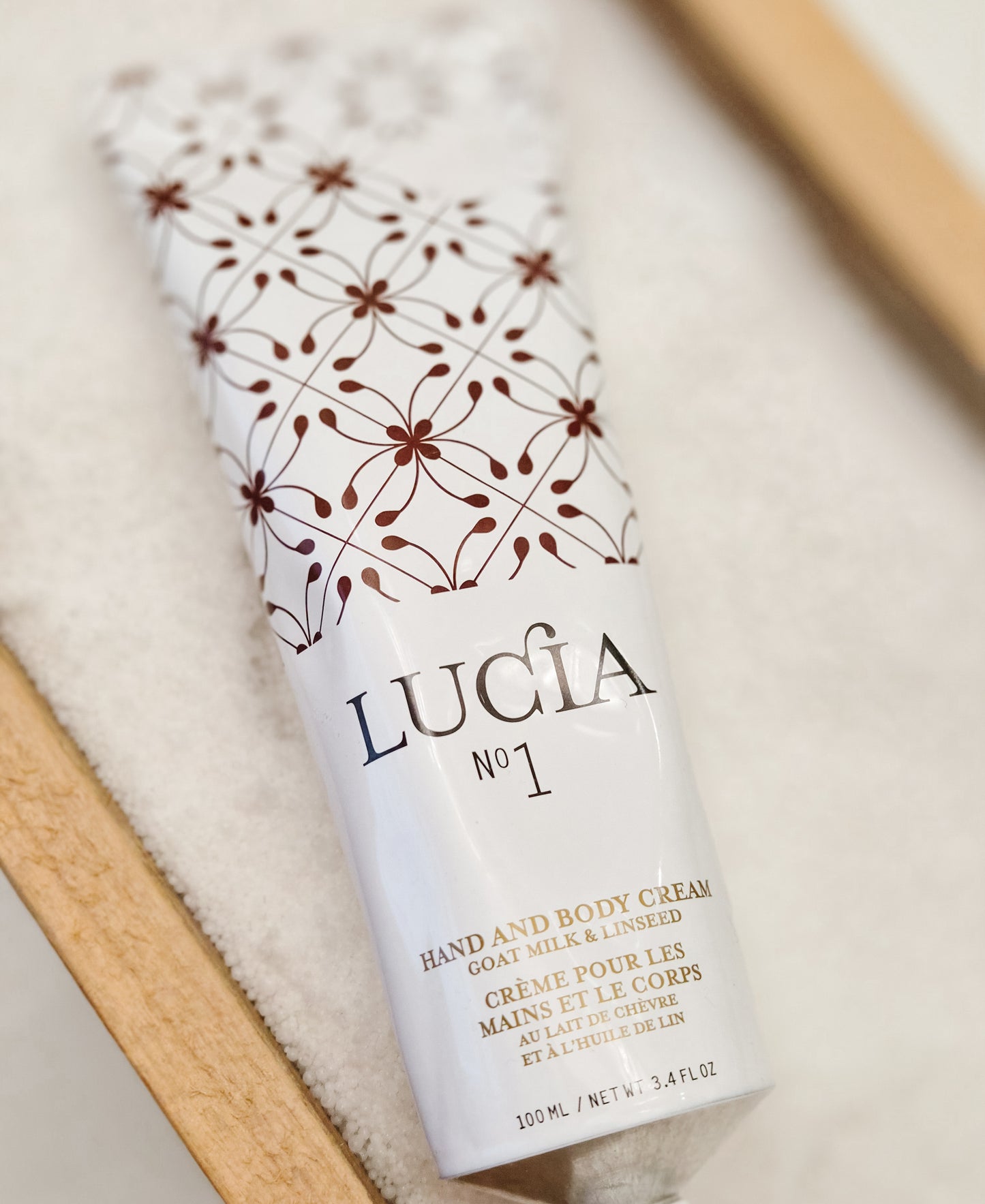 Lucia hand and body cream tube with decorative packaging on a light background