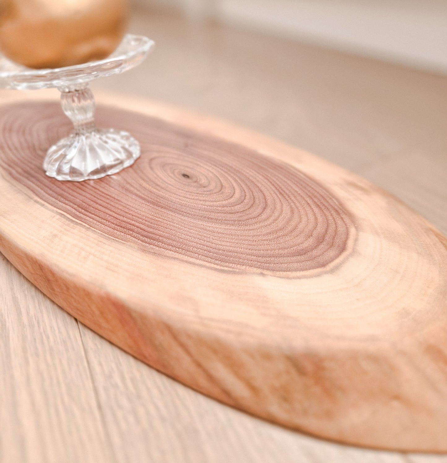 Wooden cutting board with a clear glass object on a light wooden surface
