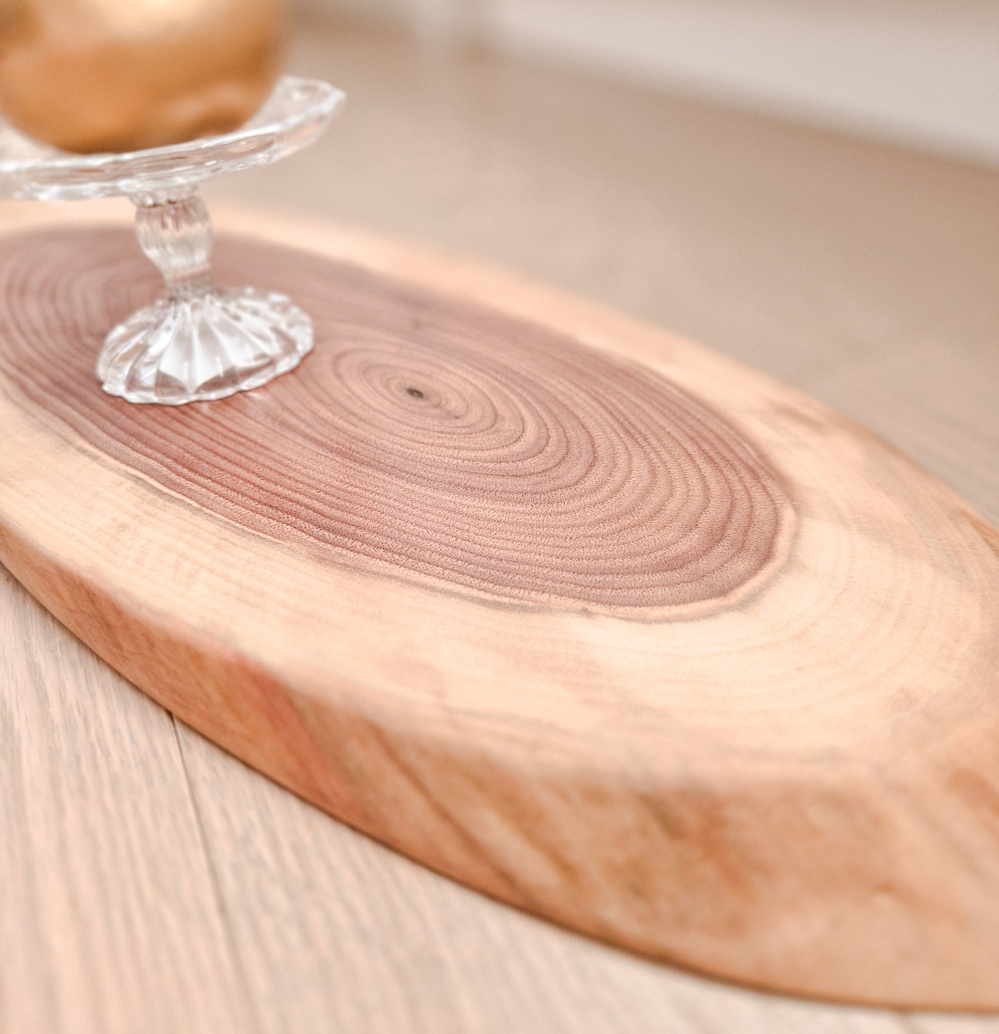 Wooden cutting board with a clear glass object on a light wooden surface