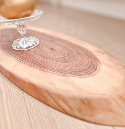 Wooden cutting board with a clear glass object on a light wooden surface