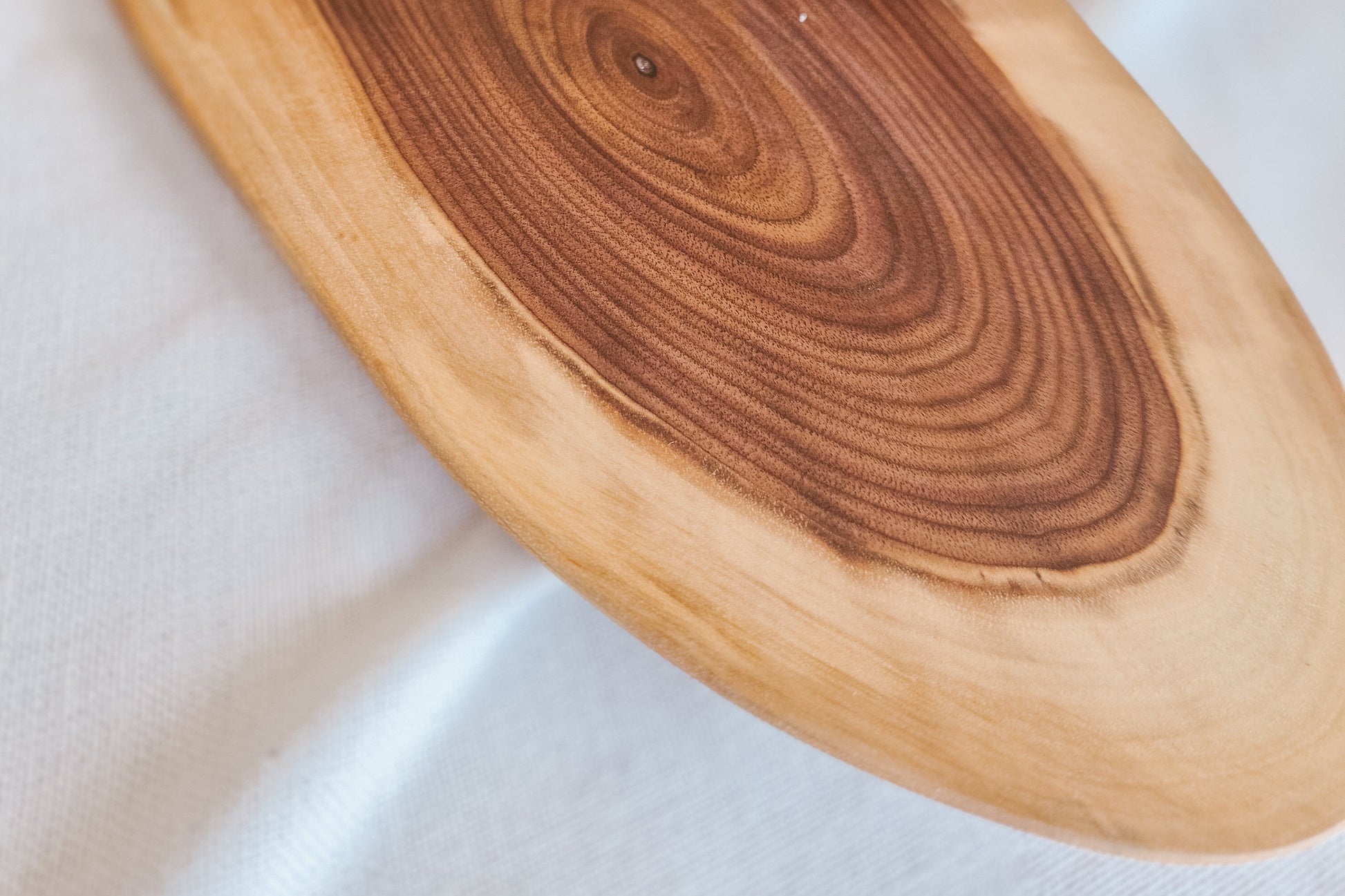 Close-up of a wooden cutting board with visible grain patterns on a white surface.