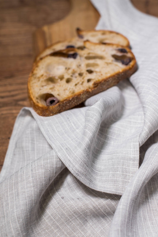 Two slices of bread with raisins on a wooden board with a white cloth underneath.