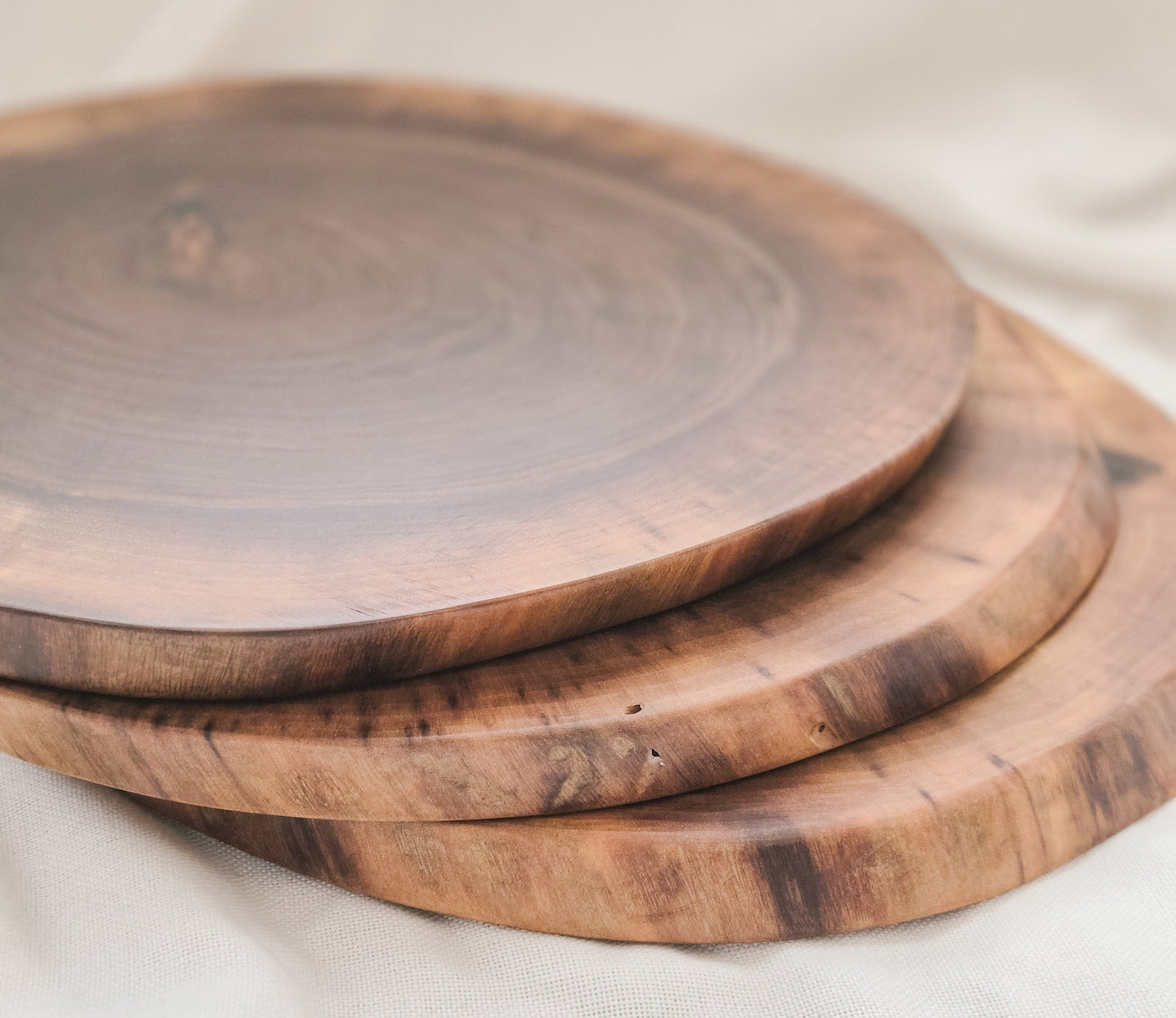 Three wooden cutting boards of different sizes on a light fabric background