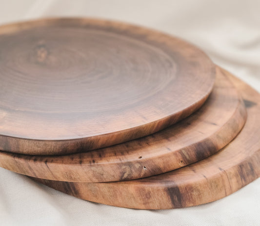 Three wooden cutting boards of different sizes on a light fabric background